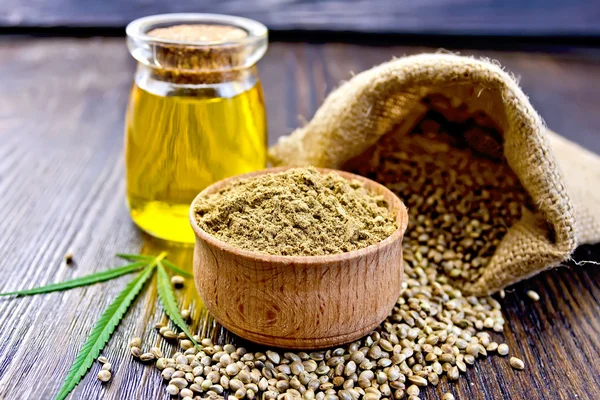 Flour hemp in bowl with grain and oil on board — Stockfoto