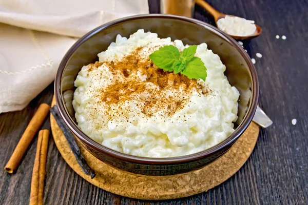 Rice porridge with cinnamon in bowl on dark board — Stockfoto