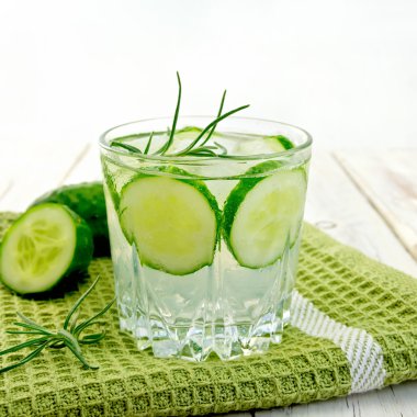 Lemonade with cucumber and rosemary in glassful on napkin and bo