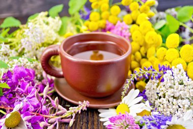 Tea from flowers in clay cup on dark board