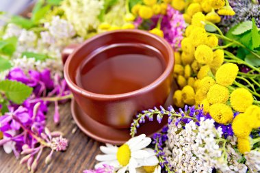 Tea from wild flowers in clay cup on board