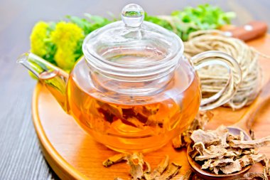 Tea of Rhodiola rosea in glass teapot on tray with spoon clipart