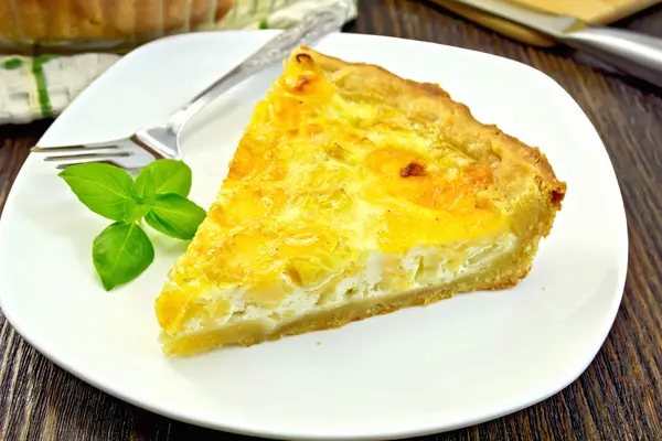 Pie with cheese and leeks in plate on board — Stock Photo, Image