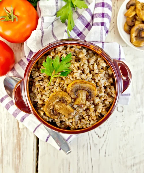 Buckwheat with champignons in clay bowl on board top — Stock Photo, Image