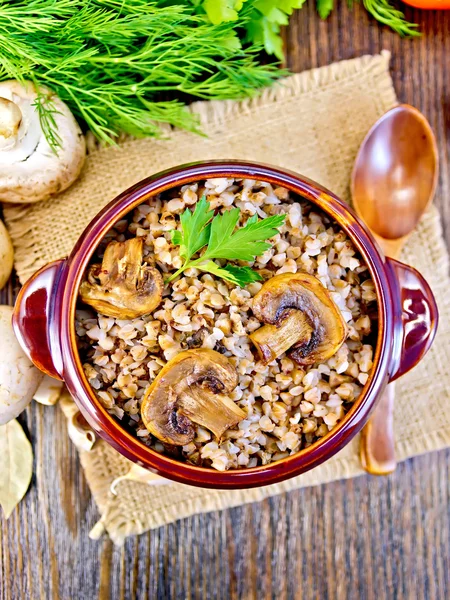 Buchweizen mit Champignons in Tonschale auf Tischplatte — Stockfoto