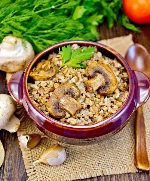 Buckwheat with champignons in clay bowl on sacking — Stock Photo, Image