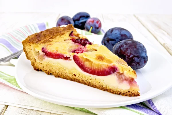 Pie plum with sour cream in plate on light board — Zdjęcie stockowe