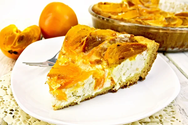 Tarta con cuajada y caquis en plato blanco sobre servilleta de silicona —  Fotos de Stock