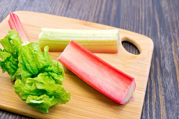 Rhubarb with leaf on dark board — Stock Photo, Image