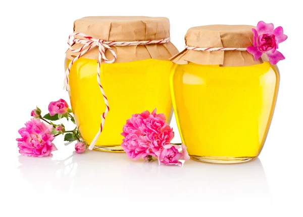 Miel en dos frascos de vidrio y flores aisladas sobre fondo blanco — Foto de Stock
