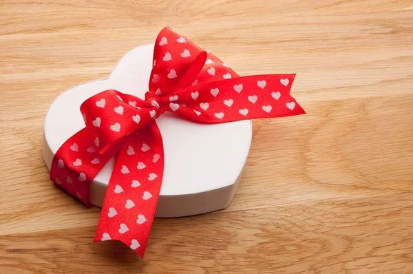 Gift in the form of heart tied with red ribbon with a bow on woo — Stock Photo, Image