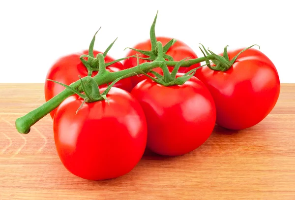 Tomates vermelhos em um ramo na tábua de madeira — Fotografia de Stock