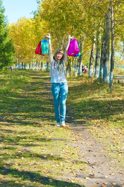 Flickan med flerfärgade paket pågår park — Stockfoto