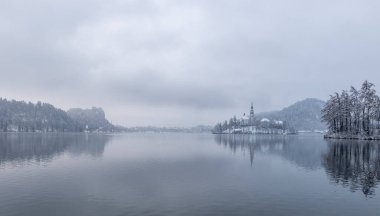 Kışın akan göl, Slovenya 'da kar ve sisli Bled Adası manzarası.