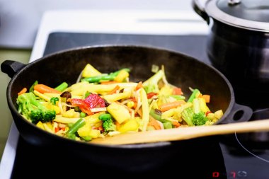 Bir tavada donmuş sebzeler, indüksiyon fırınında yeniden ısıtılır.
