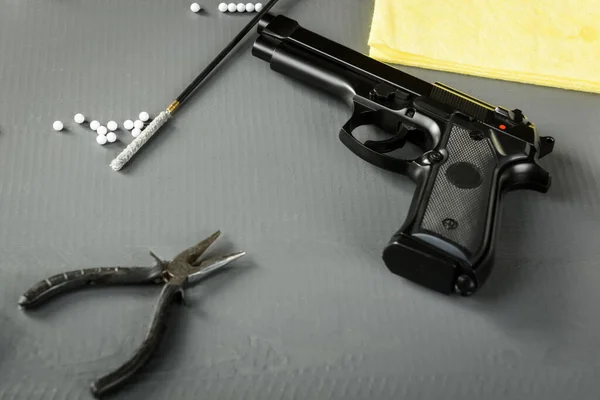 Cleaning the gun is an important part of ASG games. A working weapon is an element of a successful game. Disassembled pistol on a wooden table.