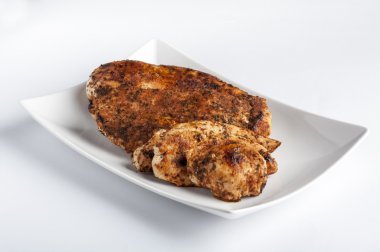 Beyaz tabakta ızgara tavuk göğsü.