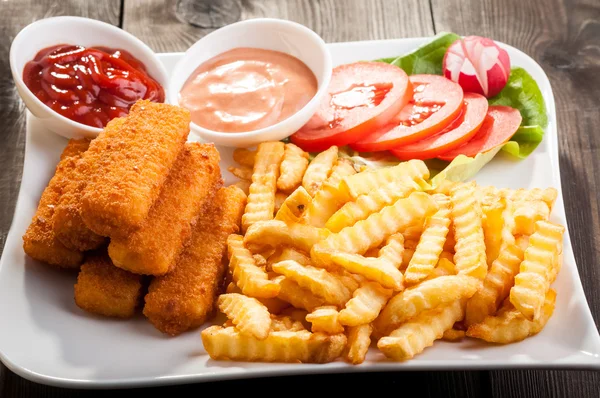 Palitos de pescado con verduras en un plato blanco — Foto de Stock