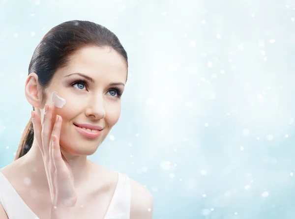 Mujer que aplica crema en su cara - facial de invierno — Foto de Stock