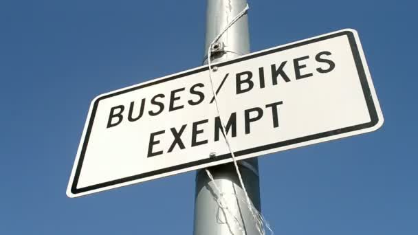 Buses, bikes exempt road sign on metal high pylon on blue sky, — Stock Video