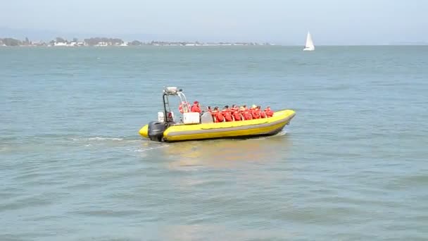 Lidé v červené barvě jednotná žlutá člunu na vlnách azurové moře v San Francisco, Usa. — Stock video