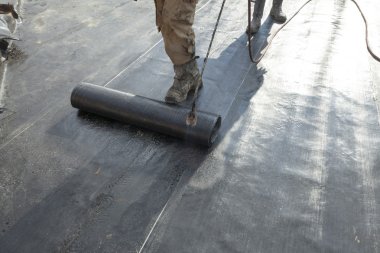 waterproofing roll bituminous material in the trench. constructi clipart