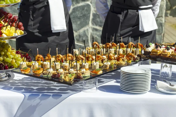 Carne de prato, peixe, canapés vegetais em uma mesa de casamento festiva ao ar livre — Fotografia de Stock