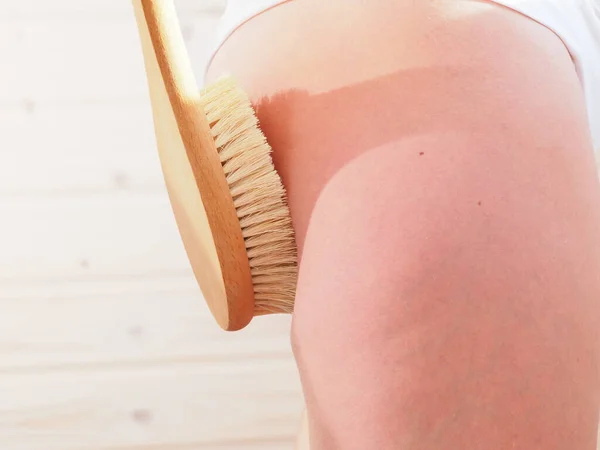 woman doing anti-cellulite massage with a brush at home