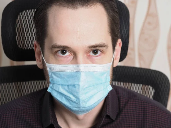 医療マスクの男がオフィスの椅子に座って肖像画の顔を閉じて — ストック写真