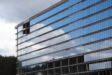 Belarus, Minsk, 2021. Tamamlanmamış cam bina cephesi akşam gökyüzünün arka planına karşı.