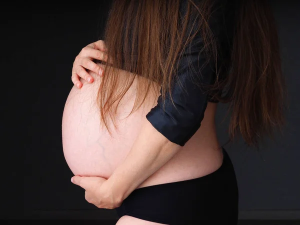 Zwanger Vrouw Houden Haar Buik Een Donkere Achtergrond Met Haar — Stockfoto