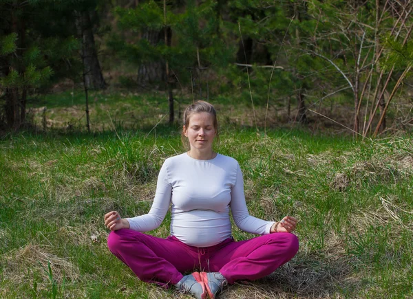 Mujer embarazada joven haciendo yoga — Foto de Stock