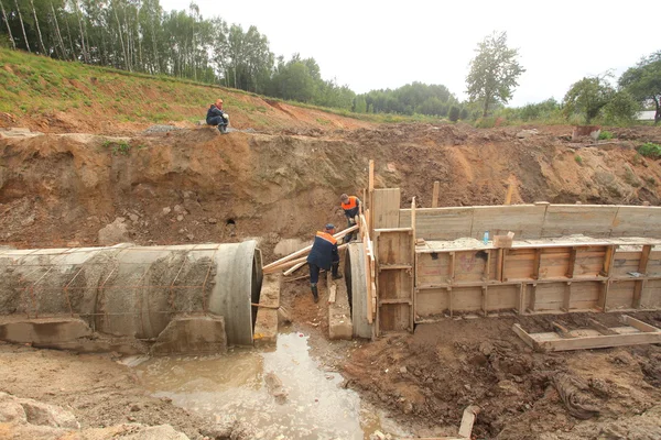 Munkavállalók kollektor fektetése beton csövek — Stock Fotó