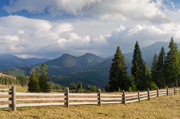 Summer landscape with a wooden fence in a mountain village — Stock Photo, Image