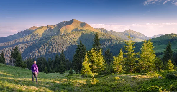 Touriste homme est debout sur une colline dans les montagnes — Photo