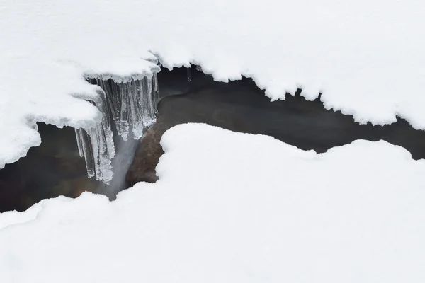 Vackra istappar och snö nära bäcken — Stockfoto