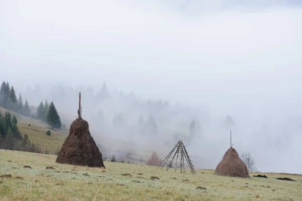 Paisaje otoñal con pajar y niebla en las montañas —  Fotos de Stock