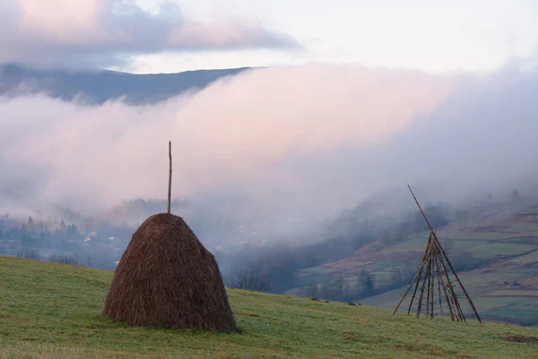 Paisaje otoñal con pajar y niebla en las montañas — Foto de Stock