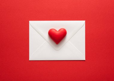 Minimalist Sevgililer Günü kartı, kırmızı renkli, kalbi beyaz zarflı. Düz yatış, üst görünüm