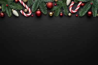 Tatil sınırında siyah bir arkaplan, Noel baloları ve Noel tasarımı için şeker kamışı. Düz konum, üst görünüm ve metin için boşluk kopyala