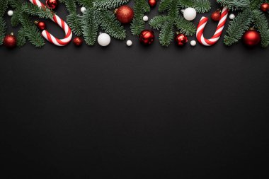 Noel arkaplanı, köknar süsü, şeker kamışı ve Noel toplarından yapılmış dekoratif kenarlı.