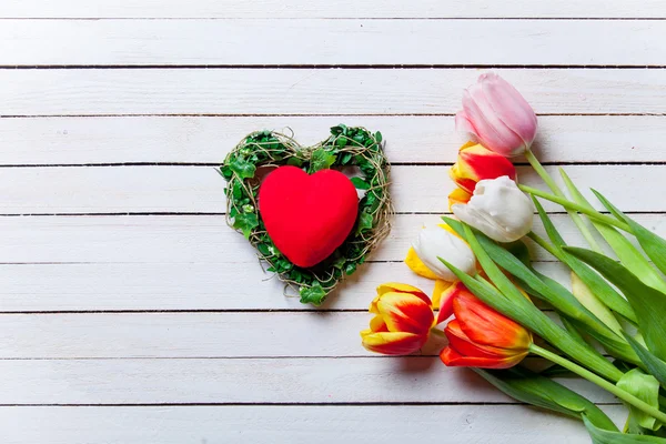 Kytice tulipánů a dárek tvar srdce — Stock fotografie
