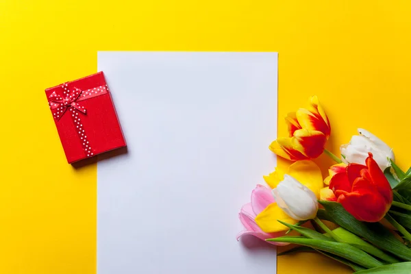 Tulipes et papier avec cadeaux sur jaune — Photo