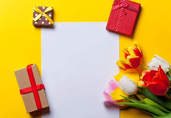 Tulipanes y papel con regalos en amarillo — Foto de Stock