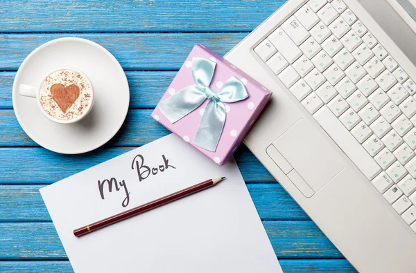 Paper, gift, coffee and laptop lying on the table — Stock Photo, Image