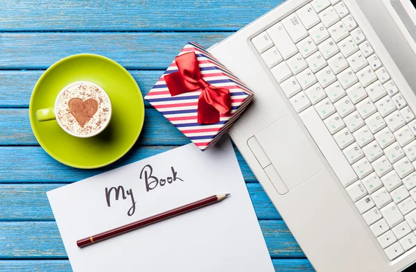 Papel, presente, café e laptop deitado sobre a mesa — Fotografia de Stock