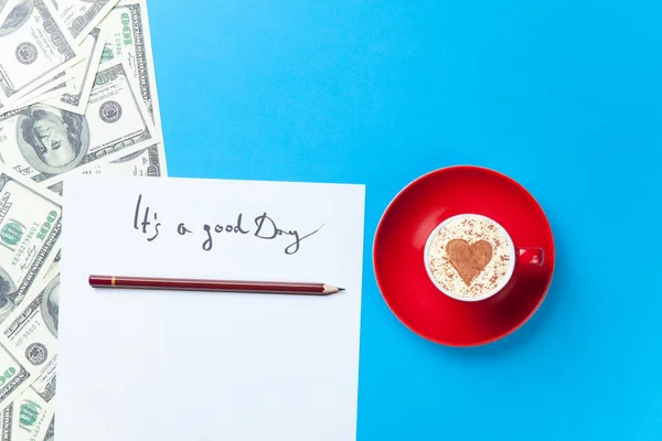 Papel, dólares y taza tumbados sobre la mesa — Foto de Stock