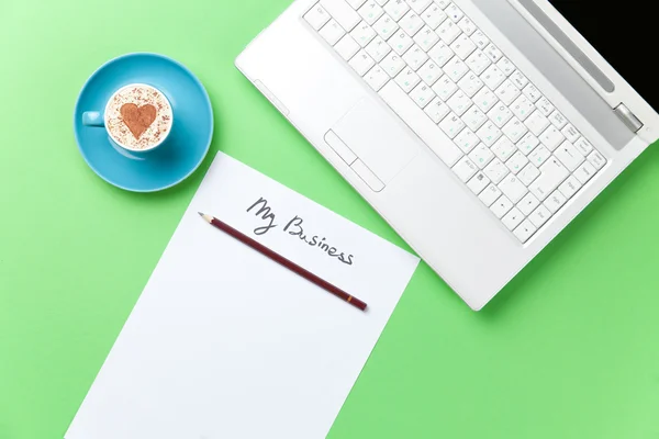 Koffiekopje en laptop liggend op de tafel — Stockfoto