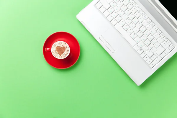 Taza y portátil acostado en la mesa — Foto de Stock