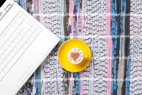 Taza y portátil acostado en la mesa — Foto de Stock